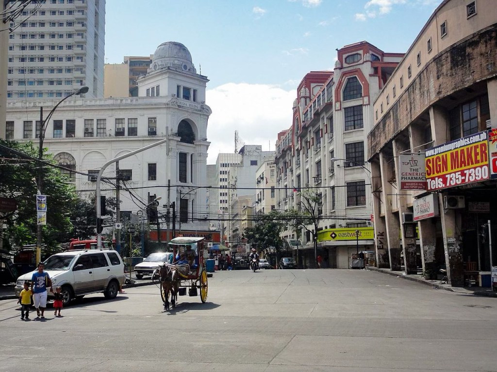 A busy street scene in the Philippines showcasing a mix of modern and historical architecture, with vehicles and pedestrians interacting in the urban environment.