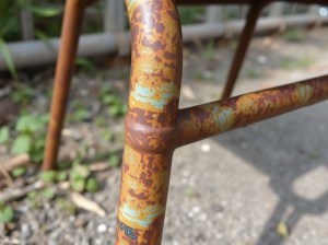 Close-up of a rusted metal furniture frame, showcasing significant corrosion and peeling paint.