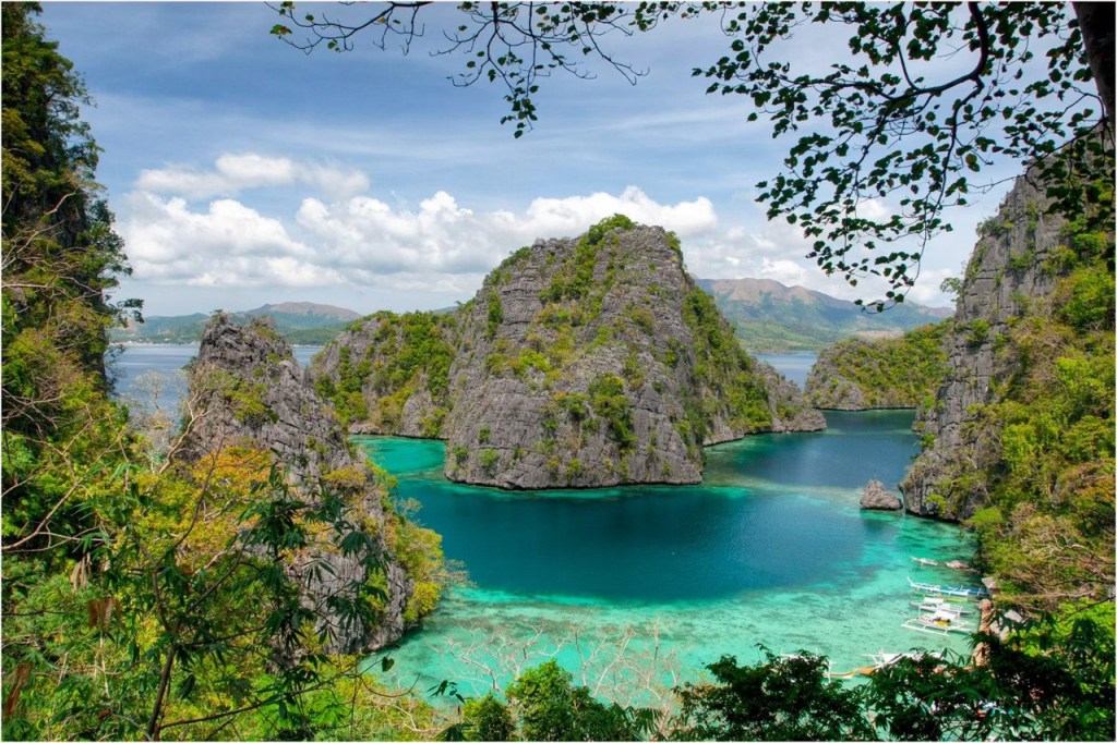 A picturesque view of limestone cliffs surrounded by clear turquoise waters in a tropical setting, showcasing the natural beauty of the Philippines.