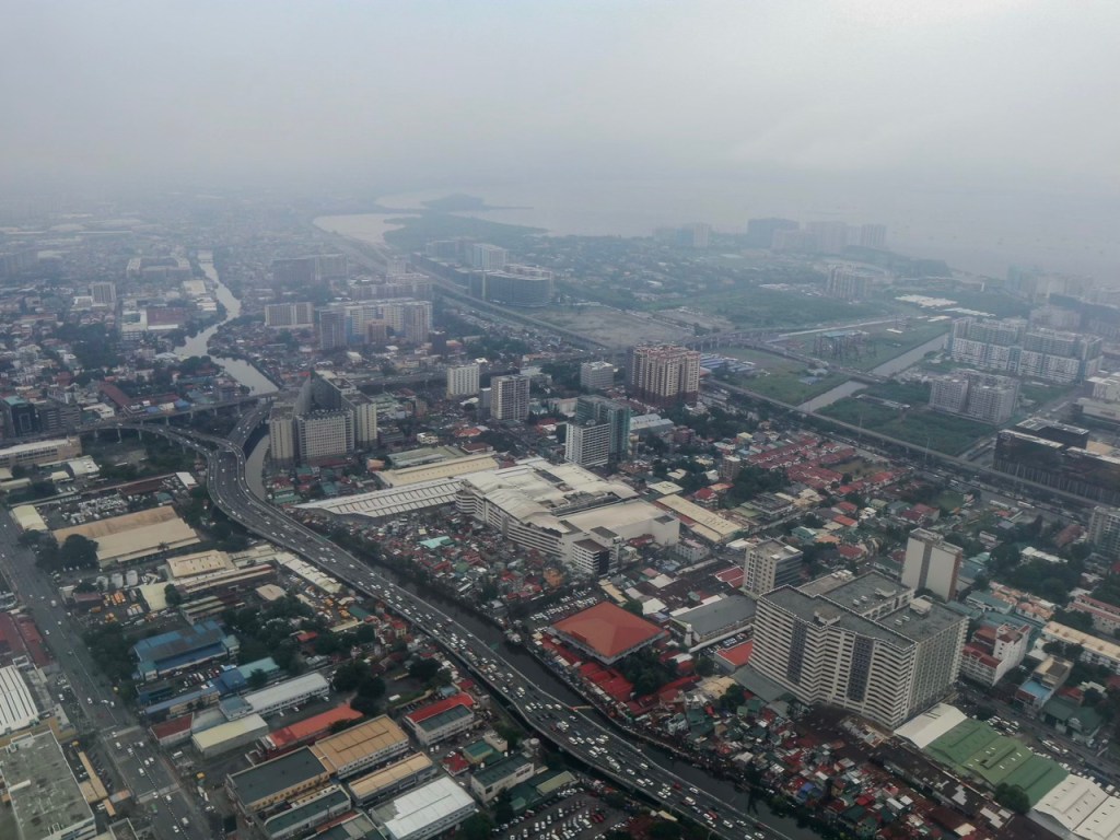 Aerial view of a densely populated urban area with buildings, roads, and a river, shrouded in foggy weather.